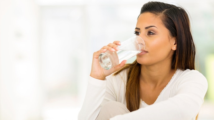 Fille buvant de l'eau et regardant dans le vide