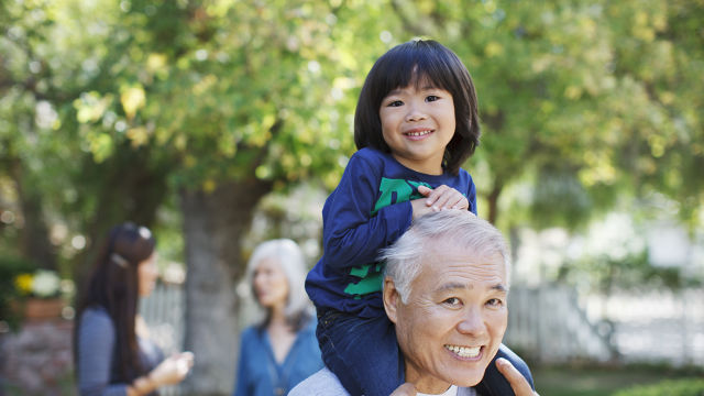 Grand-père avec sa petite-fille sur les épaules dans un parc